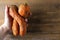 Two dirty ugly carrots in human hand on brown old wooden background with copy space. Vegetables with unusual strange