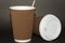 Two disposable cups for hot drinks on a dark backgrounds. Paper cups and white cap with the inscription Caution Contents Hot! .