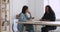 Two diverse businesswomen talking sit at office table