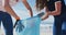 Two diverse female friends putting rubbish in refuse sacks at the beach