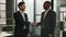 Two diverse multiracial businessmen business colleagues partners men handshaking in office posing smiling to camera