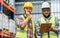 Two diverse professional male workers holding board, checking shipping stocks in storage, warehouse or factory for delivery,