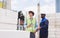 Two diversity male engineers team working, inspecting outdoor at construction site, wearing hard hats for safety, talking,