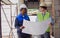 Two diversity male engineers team working, inspecting outdoor at construction site, wearing hard hats for safety, talking,