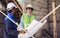 Two diversity male engineers team working, inspecting outdoor at construction site, wearing hard hats for safety, talking,