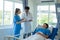 Two doctors caring for a patient lying in a bed in a hospital room with two nurses, a healthcare worker