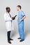 Two doctors meeting and consulting each other on gray background. Caucasian doctor and afroamerican doctor talking abount pacient