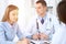 Two doctors and patient sitting at the table in medical cabinet.