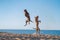 Two dogs on the beach. Active pit bull terrier jumping on the background of the sea