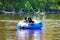 two dogs ride a rubber raft down a stream in a wooded area