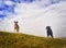 Two dogs wait on a hilltop to continue their walk