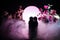 Two doll hugging on table with flowers and moon decoration Lighted background with smoke.Love concept. Greeting or gift card desig