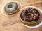 Two donuts with chocolate and tiramisu icing on a wooden table