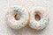 Two donuts with colorful sprinkles and glazes surface over colorful background