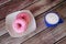 Two donuts in pink glaze on a plate and a blue cup of cappuccino on a wooden background