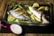 Two Dorada fish cooked in the oven with lemon, onion and green pimento in a glass dish on a black slate tray