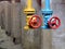 Two drain valves yellow and blue with red hand wheels over concrete elements and brown tanks background. Steampunk retro