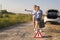 Two driver girls vote on a rural road in anticipation of help with an empty fuel tank and a hose near the car in the rays