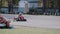 Two drivers on a go-kart track move passing by a long row of coloured tires. Go-kart race.