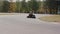 Two drivers on a go-kart track pass by the camera. Go-kart race.