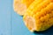 Two ears of boiled appetizing corn on a blue background/Close up. Two ears of boiled appetizing corn on a blue background. Healthy