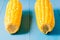 Two ears of boiled appetizing corn on a blue table/vegetarian concept. Two ears of boiled appetizing corn on a blue table. Healthy