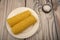 Two ears of boiled corn in a plate and coarse salt on the table. Healthy diet. Fitness diet. For a sweet treat