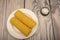 Two ears of boiled corn in a plate and coarse salt on the table. Healthy diet. Fitness diet. For a sweet treat