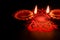 Two earthen lamps in Deepawali concept with beautiful rangoli art on black background. Festival concept