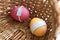 Two Easter colored eggs orange and pinl with medical masks inside a wicker backet. Easter quarantine concept