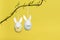 Two easter egg ornaments with bunny faces hanging on a branch on a yellow background