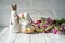 Two Easter porcelain rabbits stand on a white wooden table. In the paws rabbits hold Easter eggs. In theticipation of