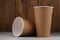 Two eco-friendly cardboard cups lie on a concrete surface on a wooden background. Mock-up. Close-up.
