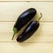 Two eggplants on a light wooden background