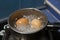 Two eggs in boiling water in stainless steel pan on the kitchen stove