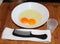 Two eggs and comb in bowl on wood surface