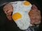 Two eggs frying sunny side up with bacon