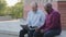 Two Elderly people sitting outdoors using laptop for work. Mature adult African American male counselor helps old