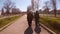 Two elderly people walk along the park avenue