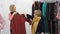 two elderly women choose and try on clothes hanging on hangers in the store