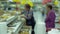 Two elderly women in a supermarket are picking up