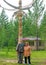 Two elderly Yakuts a man and a woman stand hugging and smiling under the national ritual pillar of Serge