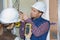 Two electricians checking voltage in wall socket
