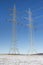 Two Electricity pylons in the winter landscape with snow field.