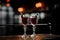 Two elegant glasses filled with fresh sweet and strong summer Arnaud cocktail on the dark blurred background of bar