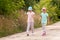 Two elementary school age girls wandering, children, sisters walking together through a country road, rural area. Taking a walk,