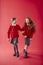 Two Elementary School Pupils Wearing Uniform Linking Arms Against Red Studio Background