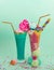 Two elicious homemade extreme milkshake, with a blackberry candy over a milk foam and a rainbow candy on top with a