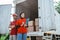 two employees in red uniforms behind a logistics container truck