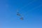 Two empty chair lift seats against blue sky